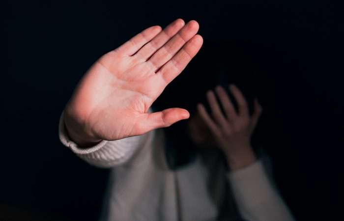 An image of a person holding their hand in front of their face and putting up their hand in a stop motion, an image paired with a blog on domestic violence